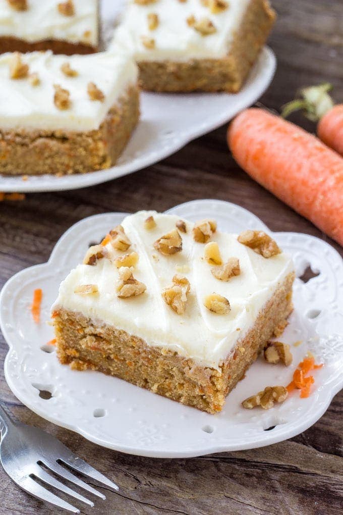 A slice of moist, chewy carrot cake bars with cream cheese frosting and chopped walnuts. 