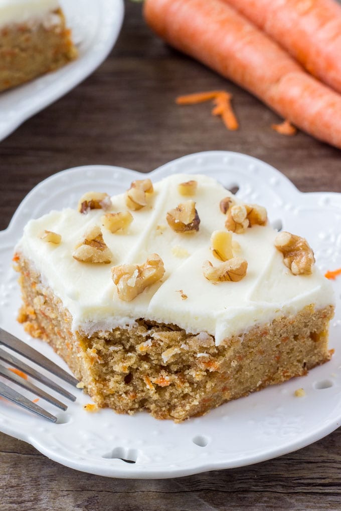 Carrot Cake Bars with Cream Cheese Frosting are chewy, dense, moist, and filled with all the flavor of your favorite carrot cake. Then they're topped with cream cheese frosting and a few chopped walnuts for the best easy dessert recipe! A slice of carrot cake bars with cream cheese frosting with a bite taken out.