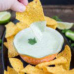 A chip dipping into a bowl of jalapeno ranch dip