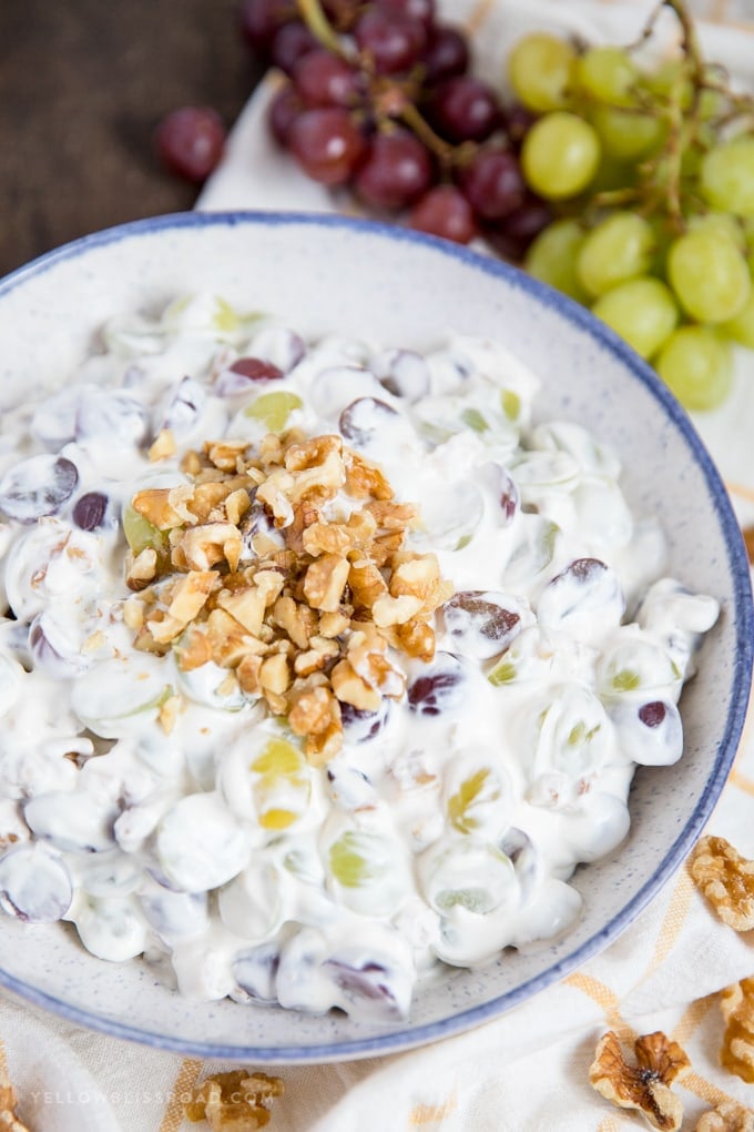 This Creamy Grape Salad with walnuts in a bowl with vines of grapes on the side