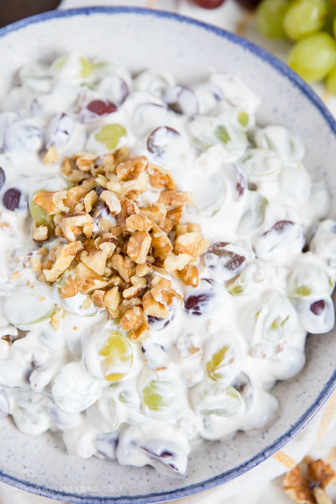This Creamy Grape Salad with walnuts is is creamy and sweet and the perfect side dish or dessert for picnics, potlucks and parties. This Creamy Grape Salad with walnuts close up in a blue bowl