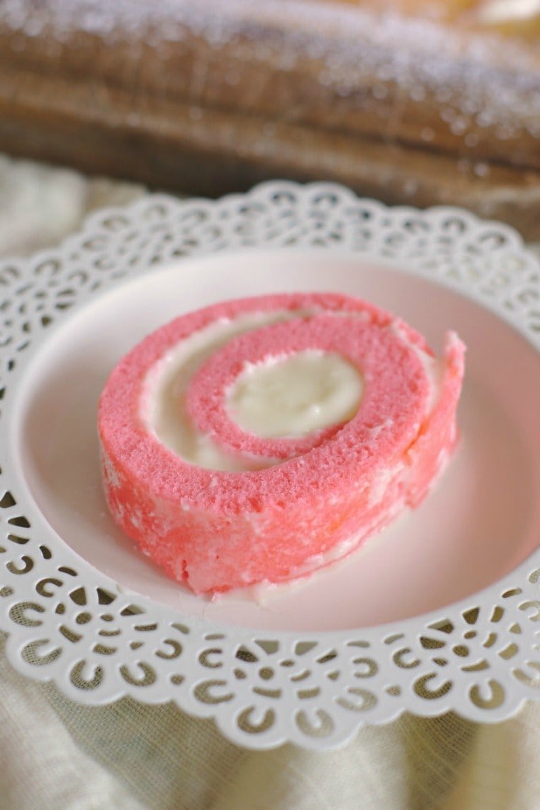 Slice on pink velvet cake roll on a dessert plate