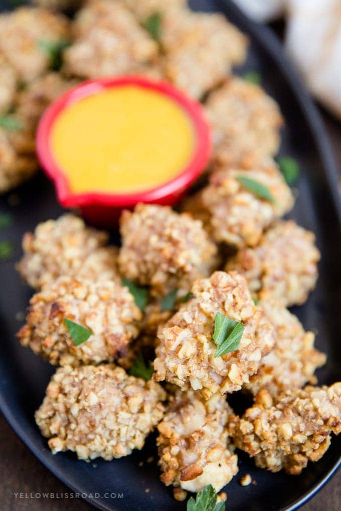 Walnut Crusted Baked Chicken Nuggets: tender, juicy chicken coated in crunchy walnuts and seasonings. Easy appetizer or dinner. #ad #californiawalnuts Walnut Crusted Baked Chicken Nuggets close up on a platter