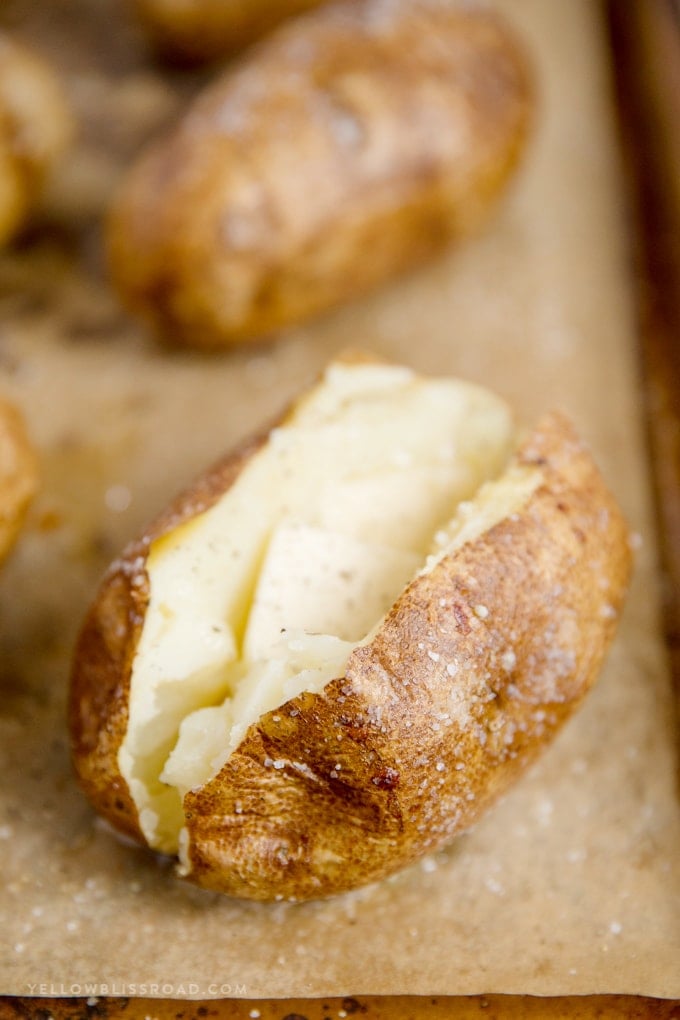 Baked potatoes are a super delicious and filling side dish for any meal. Learn how to bake potatoes in the oven with this easy recipe! Baked potato with melted butter and salt
