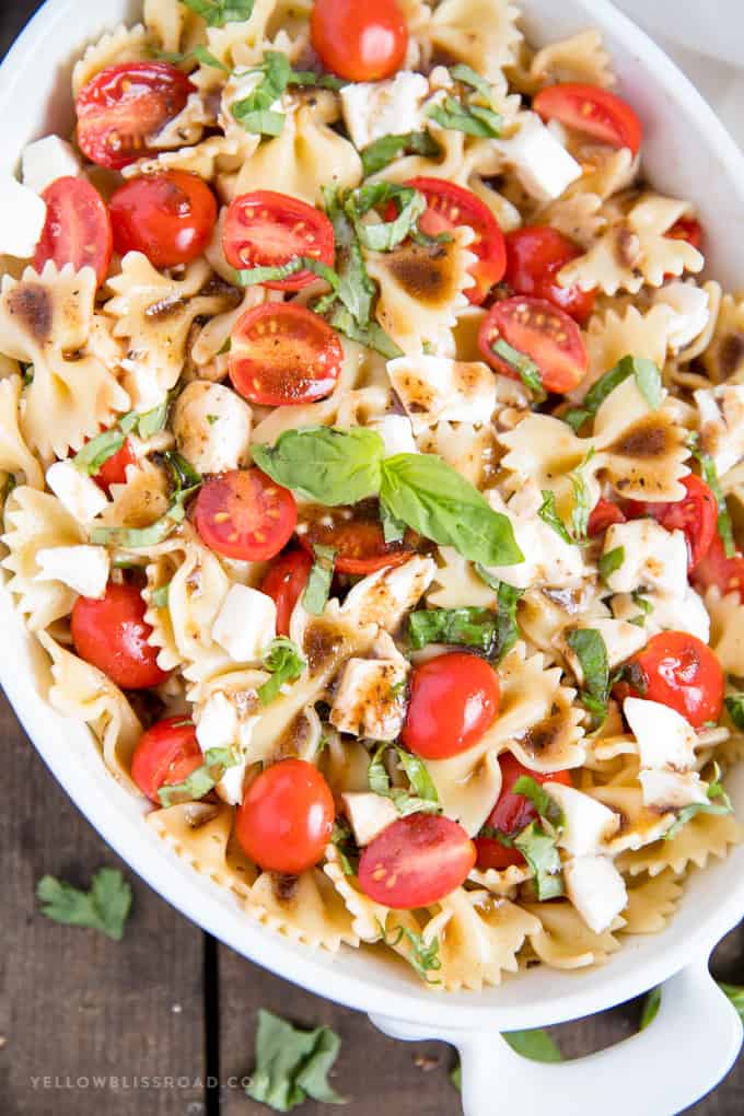 A close up photo of a Caprese Pasta Salad with mozzarella, tomatoes and basil