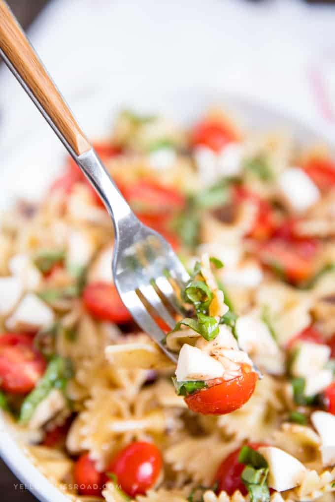 Caprese Pasta Salad with pasta, tomato and mozzarella cheese on a fork