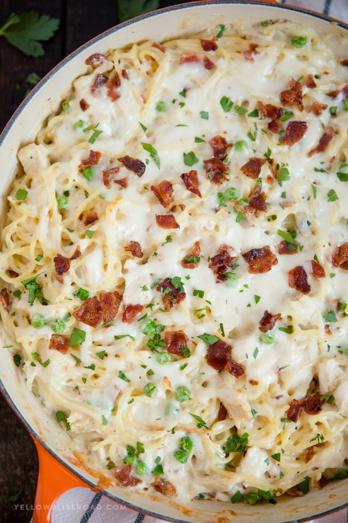 Creamy, Cheesy Chicken Spaghetti, with bacon, chicken, spaghetti and peas in a made from scratch sauce. Pure comfort food and perfect for a hearty weeknight meal. A close up overhead image of Creamy, Cheesy Chicken Spaghetti in a skillet.
