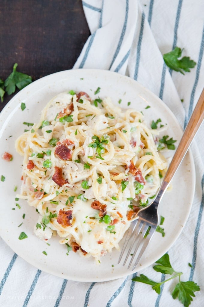 A plate of creamy chicken spaghetti with bacon, peas and a made from scratch cream soup sauce.