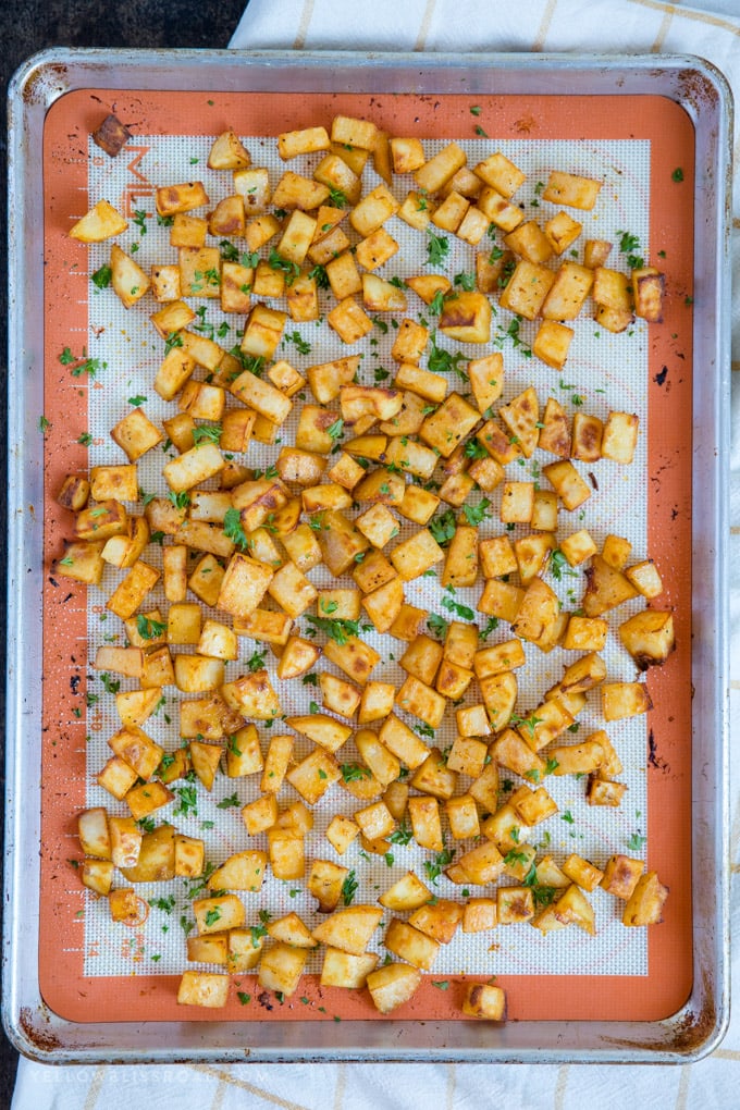 sheet pan with diced crispy breakfast potatoes on a silicone mat