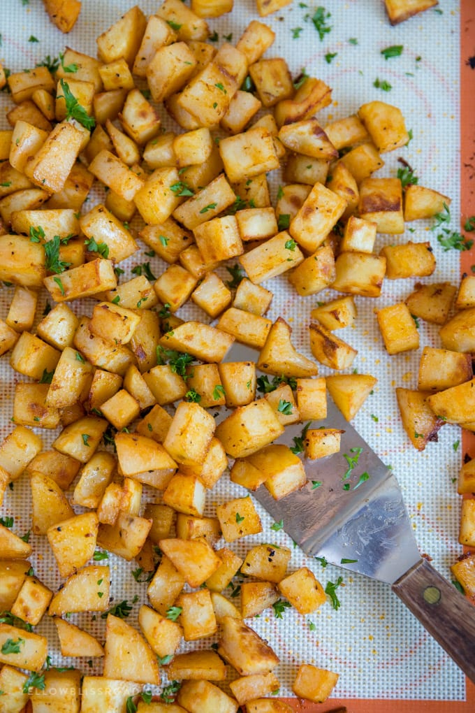 Breakfast potatoes on a silicone mat with a metal spatula