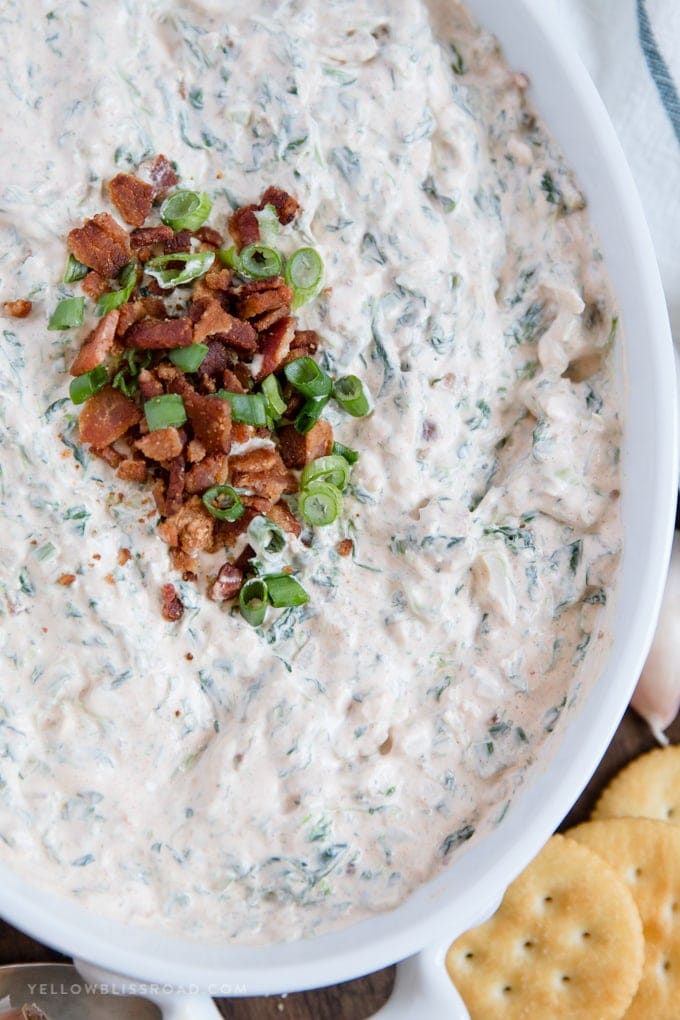 Bacon Garlic Spinach Dip with crumbled bacon and green onion garnish