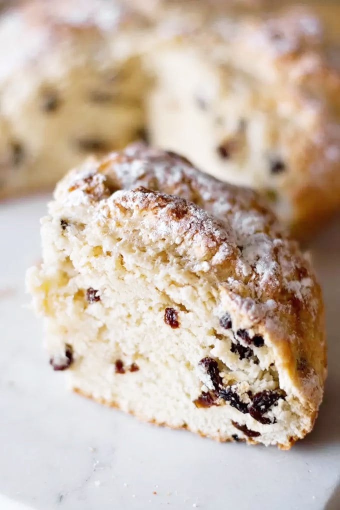 A large slice of Irish soda bread with raisins