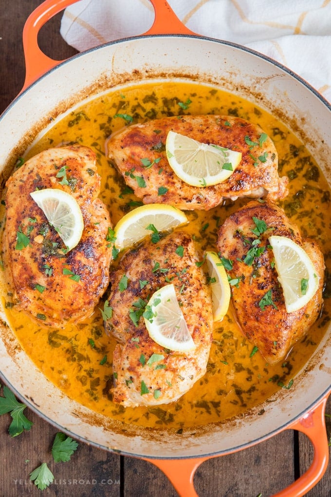 Chicken with Lemon Butter Sauce - chicken breasts in a skillet with lemon slices and parsley