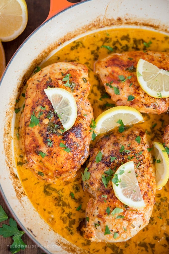 Chicken with Lemon Butter Sauce close up in a skillet with lemon slices