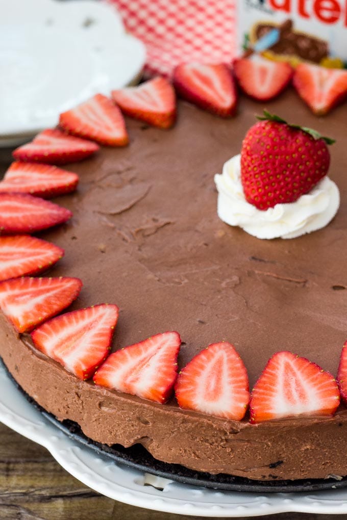 No Bake Nutella Cheesecake is smooth, creamy and filled with Nutella. It's a decadent cheesecake recipe thanks to the chocolate cookie crust and rich Nutella flavor and it's so easy to make! Nutella cheesecake topped with strawberries and whipped cream.