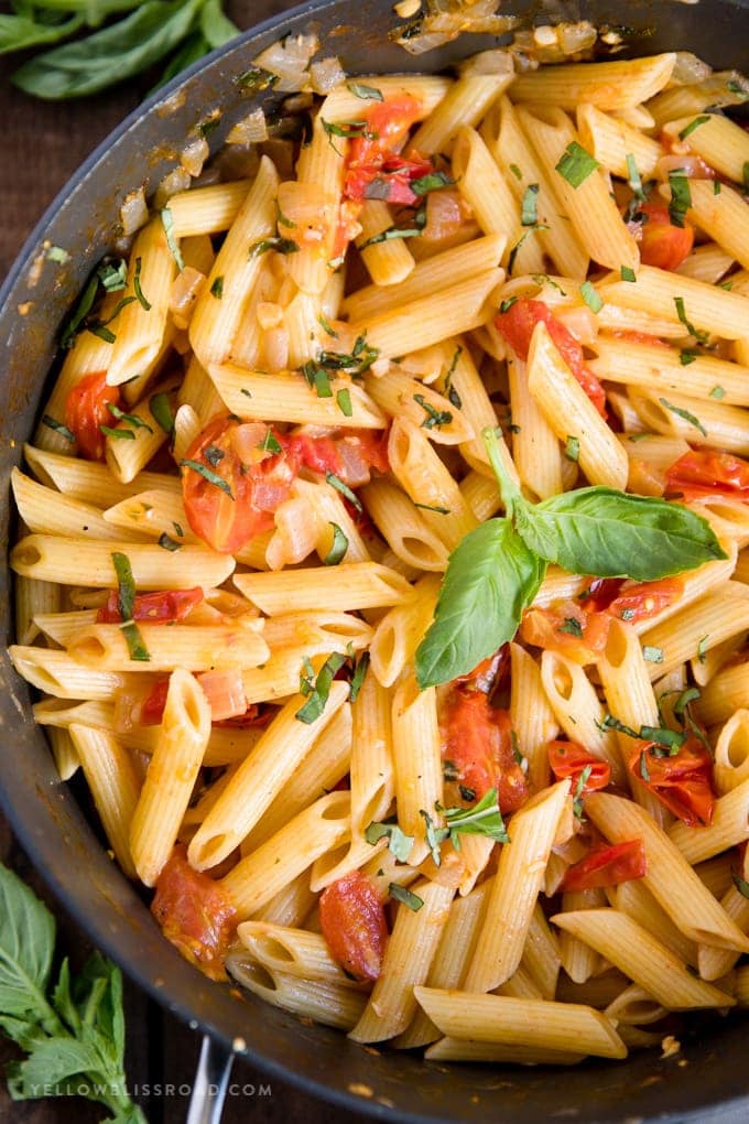 penne pasta, tomatoes and basil in a skillet.