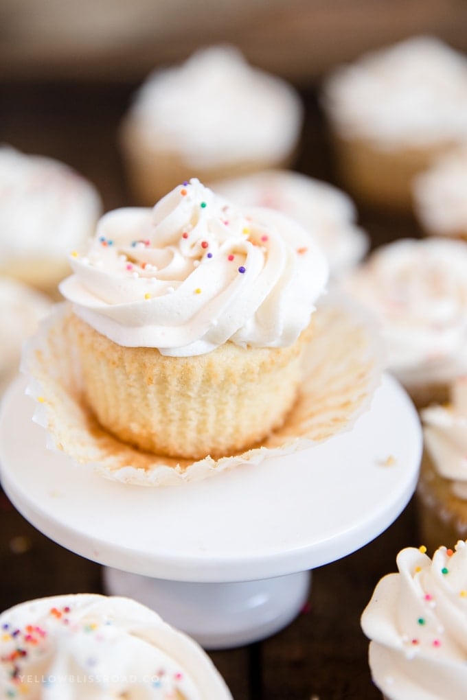 Easy Vanilla Cupcakes with Vanilla Buttercream | Dessert | Baking | Cake recipe white cupcakecake with white frosting and sprinkles on small white plate