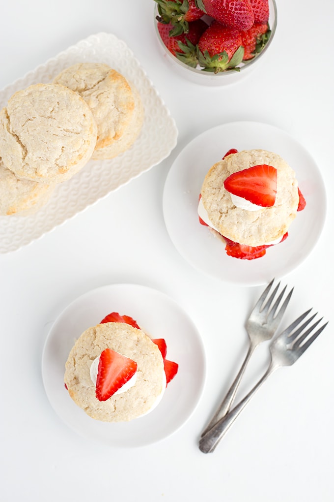 Ingredients for strawberry shortcakes and two finished shortcakes ready to eat