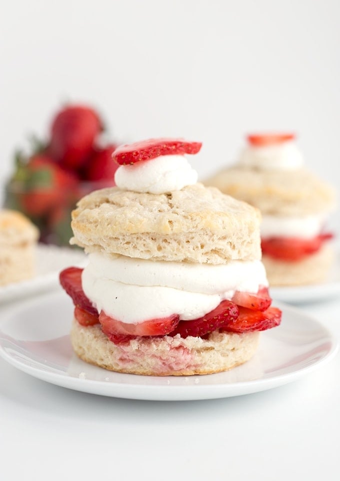 Strawberry shortcakes on dessert plates, topped with sliced strawberries