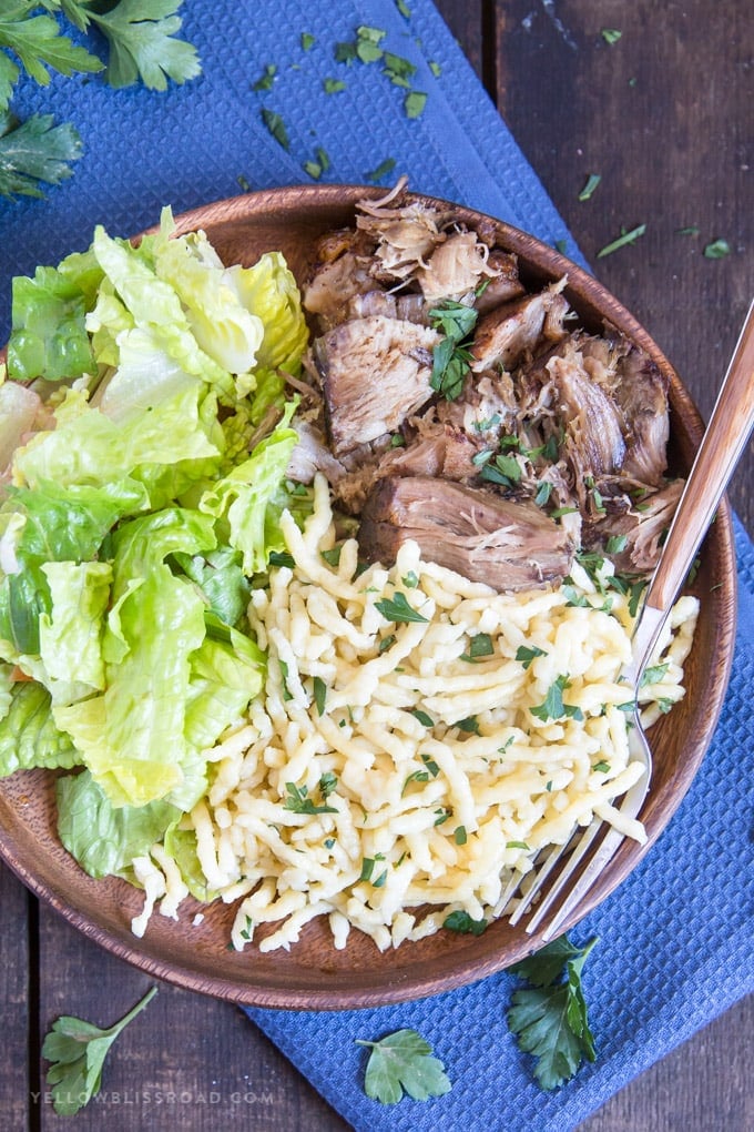 German Spaetzle on a wooden plate with pork roast and salad