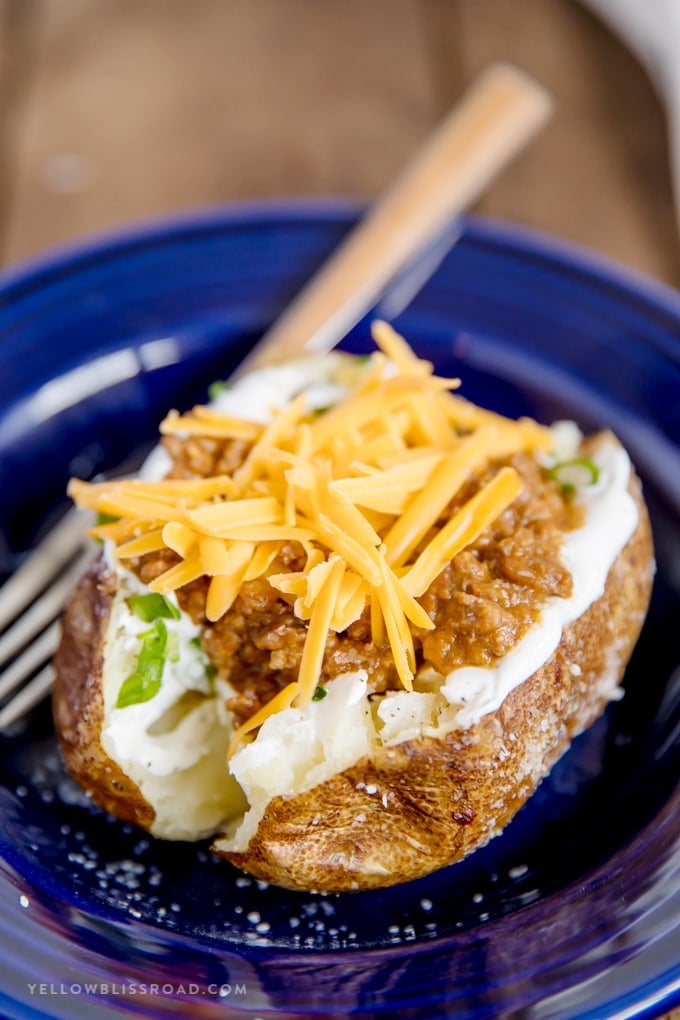 Taco Stuffed Baked Potato with cheese and taco meat in a blue pasta bowl