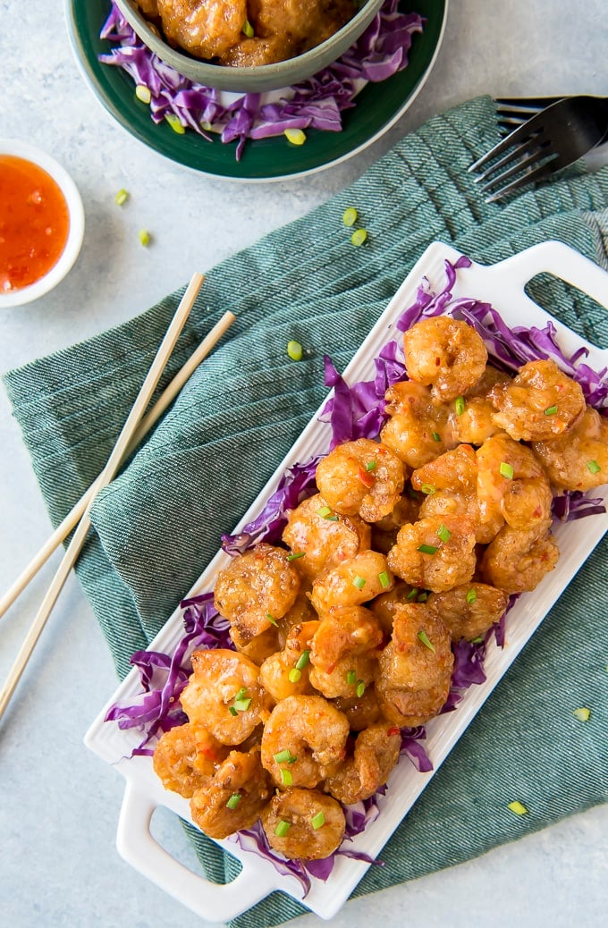 An overhead image of bang bang shrimp on a platter with chopsticks and a dish of sauce nearby