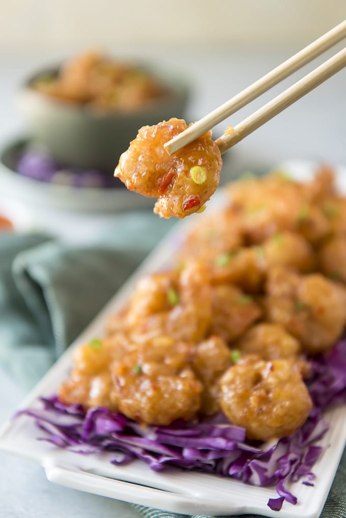 Chopsticks and fried shrimp coating in a creamy spicy sauce