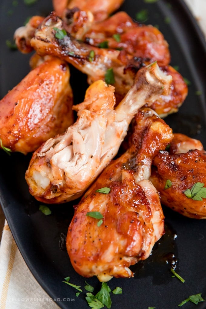 Barbecue Baked Chicken Drumsticks arranged on a black plate with a bit our of one drumstick.