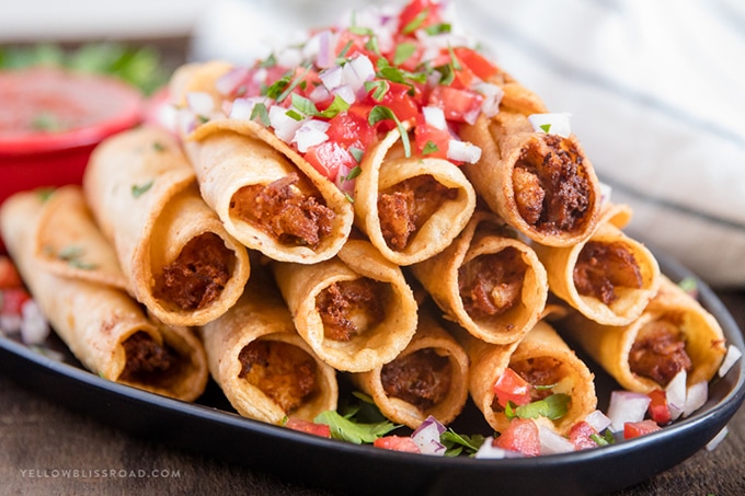 horizontal image of stacked chicken taquitos with pico di gallo garnish