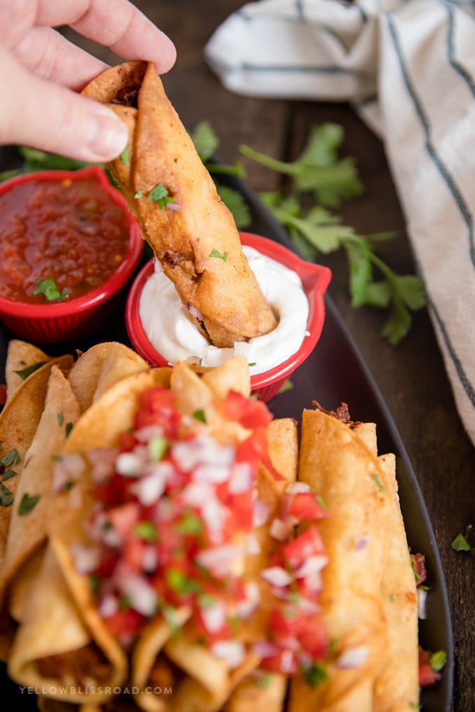 chicken taquito being dipped into sour cream