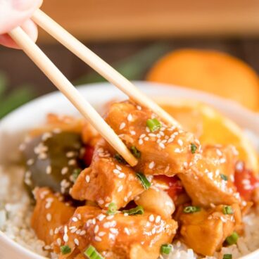 orange chicken, bell peppers, rice, sesame seeds, white bowl, chopsticks