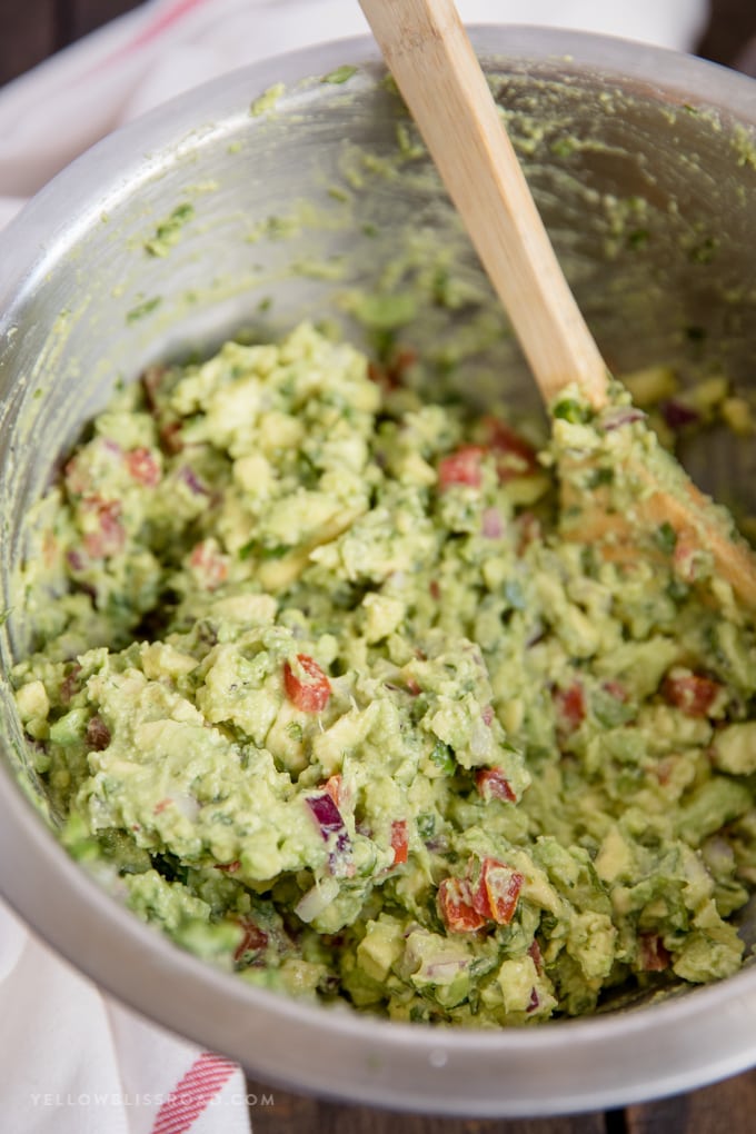 the best guacamole in a bowl with a wooden spoon