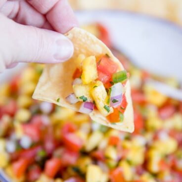 Chip dipping into bowl of Fresh Pineapple Salsa