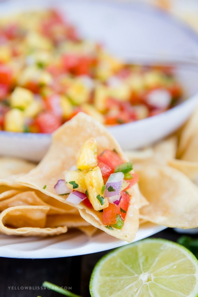 easy fresh pineapple salsa in a bowl, with some salsa scooped onto a chip