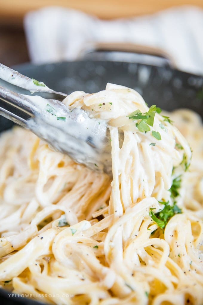 Homemade Alfredo Sauce is so creamy and flavorful, and so simple to make from scratch! Great for pasta, pizza and more! Homemade Alfredo Sauce with pasta and tongs