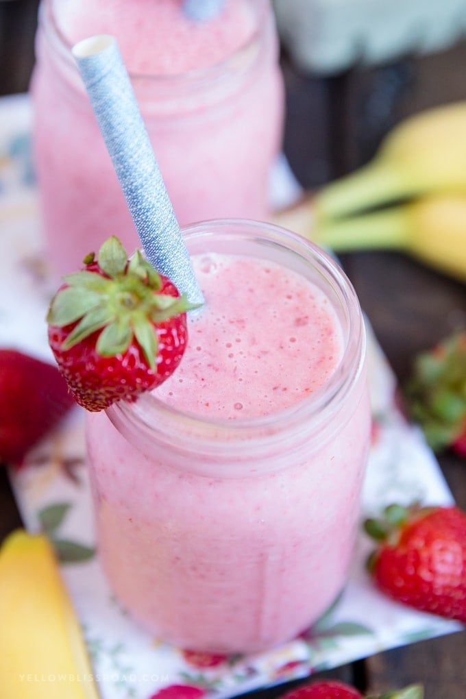 Learn how to make a Strawberry Banana Smoothie with this easy recipe! Just four ingredients for a creamy, healthy, delicious smoothie that everyone will love. banana strawberry smoothie in a glass jar with a strawberry