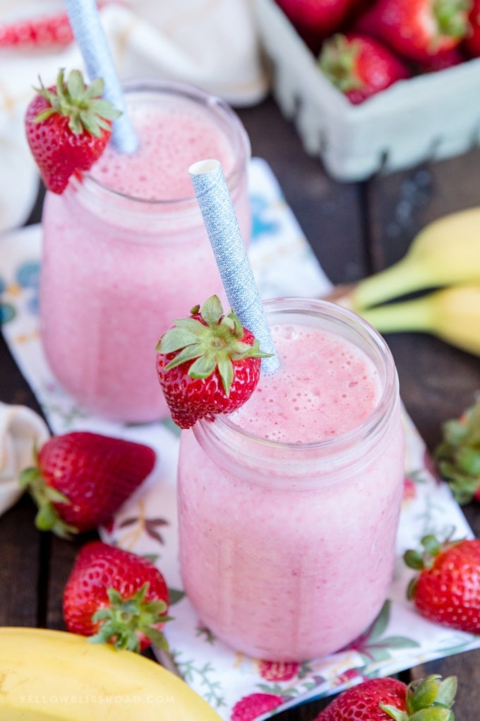 Learn how to make a Strawberry Banana Smoothie with this easy recipe! Just four ingredients for a creamy, healthy, delicious smoothie that everyone will love. Two smoothies in mason jars with strawberries and bananas