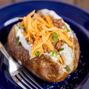 A blue plate with a taco stuffed potato