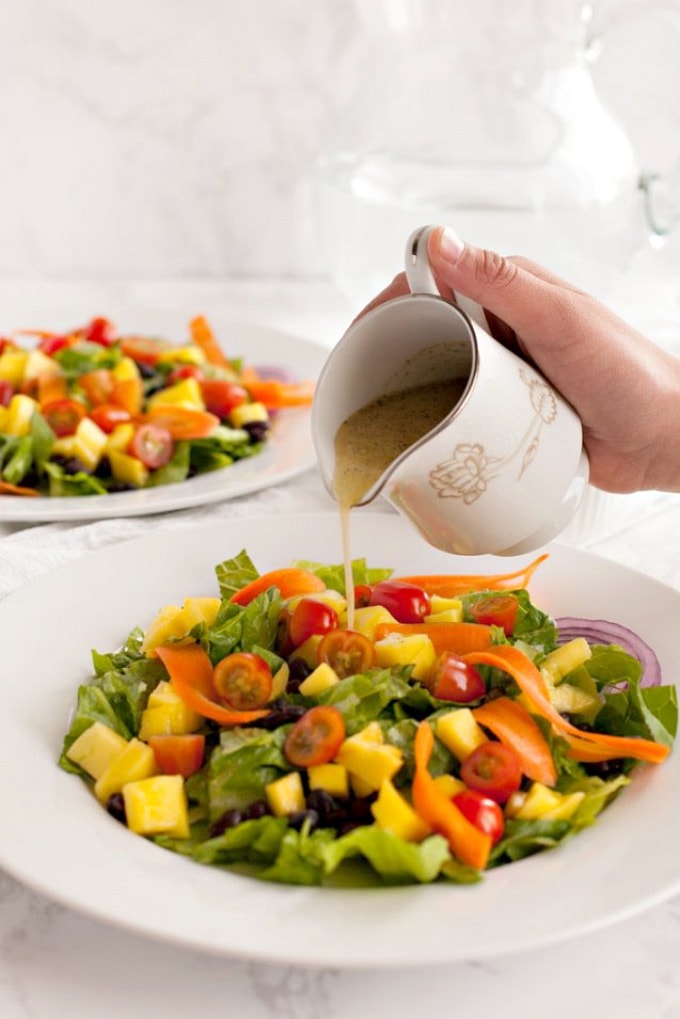 salad dressing being poured onto black bean and mango salad