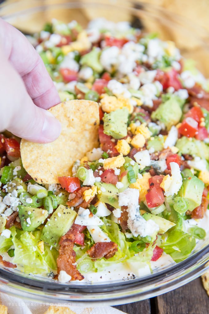 a tortilla chip dipped into a cobb salad dip