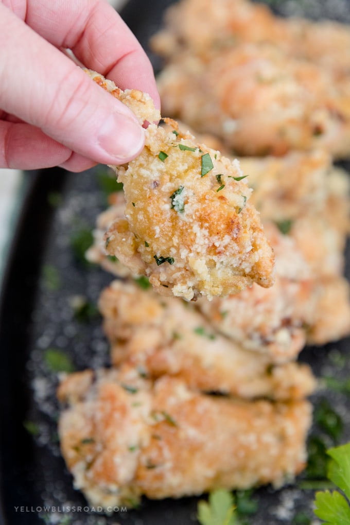 Crispy Baked Garlic Parmesan Chicken Wings in garlic parmesan sauce on a platter with one held up