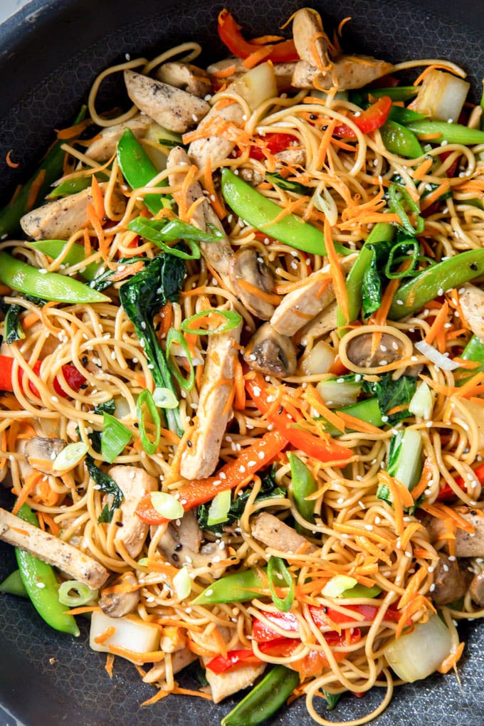 a close up overhead image of chicken lo mein with vegetables.