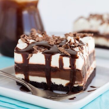 A piece of chocolate lasagna dessert sitting on a white plate with a blue napkin