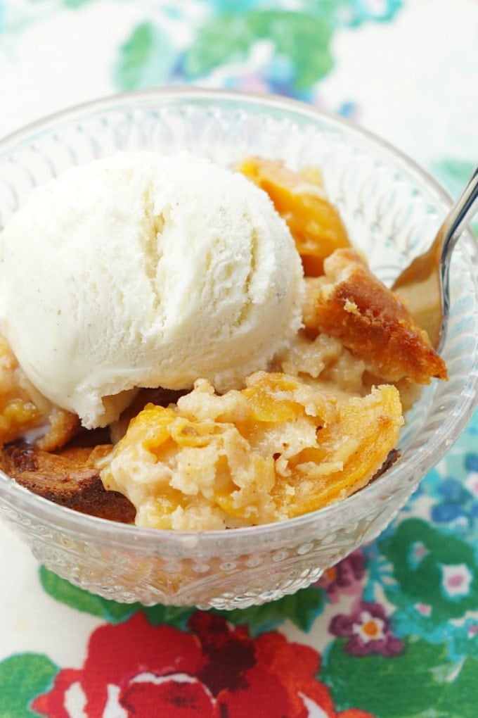 fork digging into a bowl of peach cobbler with ice cream