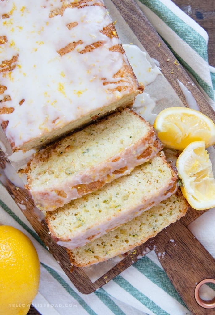 a loaf of lemon zucchini bread with three slices cut and some squeezed lemons on the side