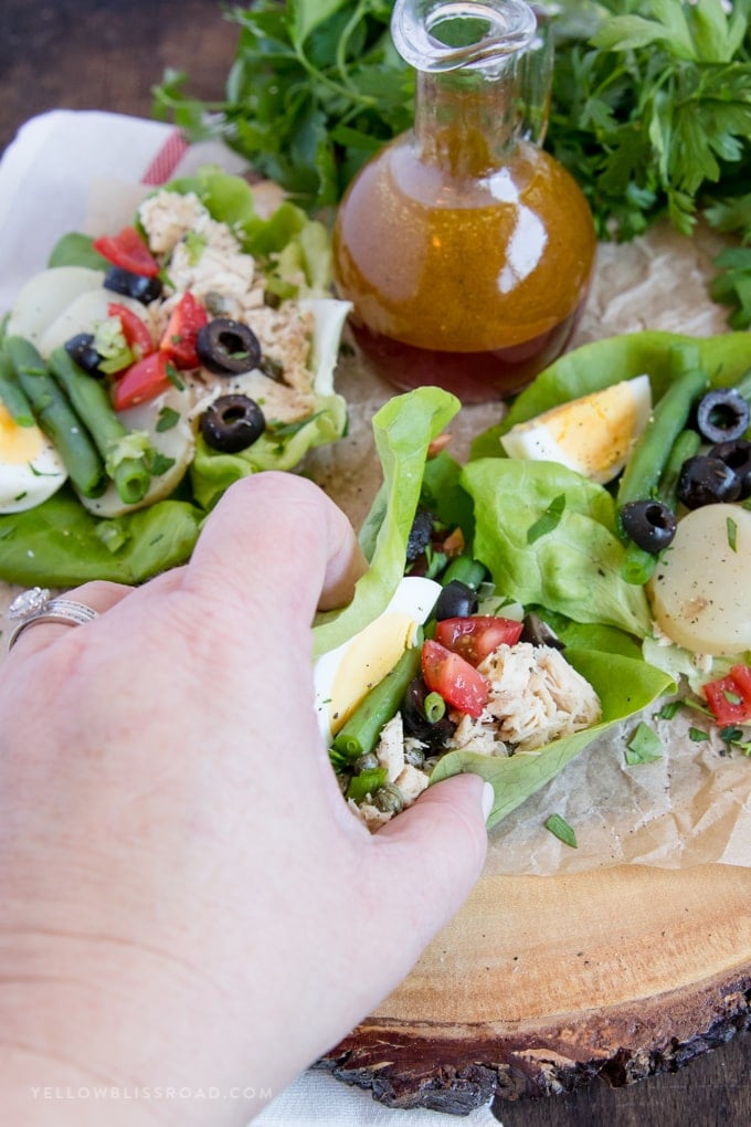 a hand picking up a Nicoise Salad Lettuce Wrap