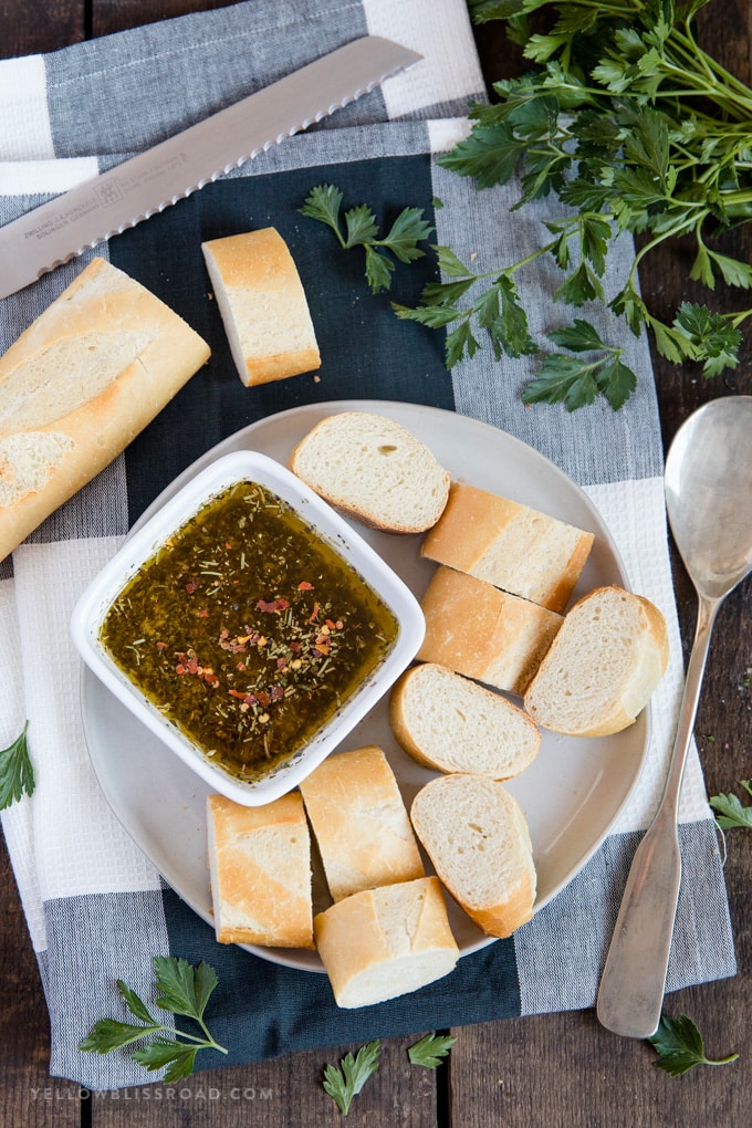 a plate of slice french bread with a dipping bowl of garlic herb olive oil bread dip