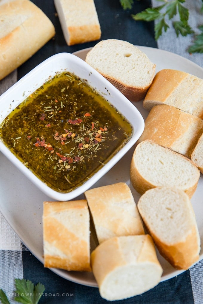 a plate of sliced french baguette with a bowl of olive oil bread dip