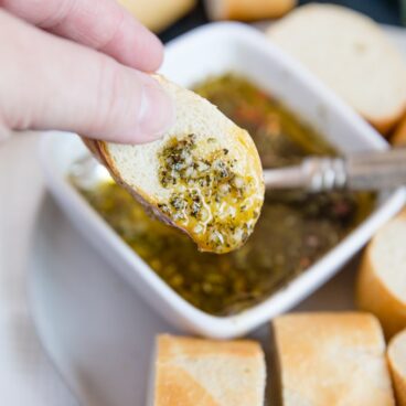 A piece of Bread dipped in olive oil and herbs