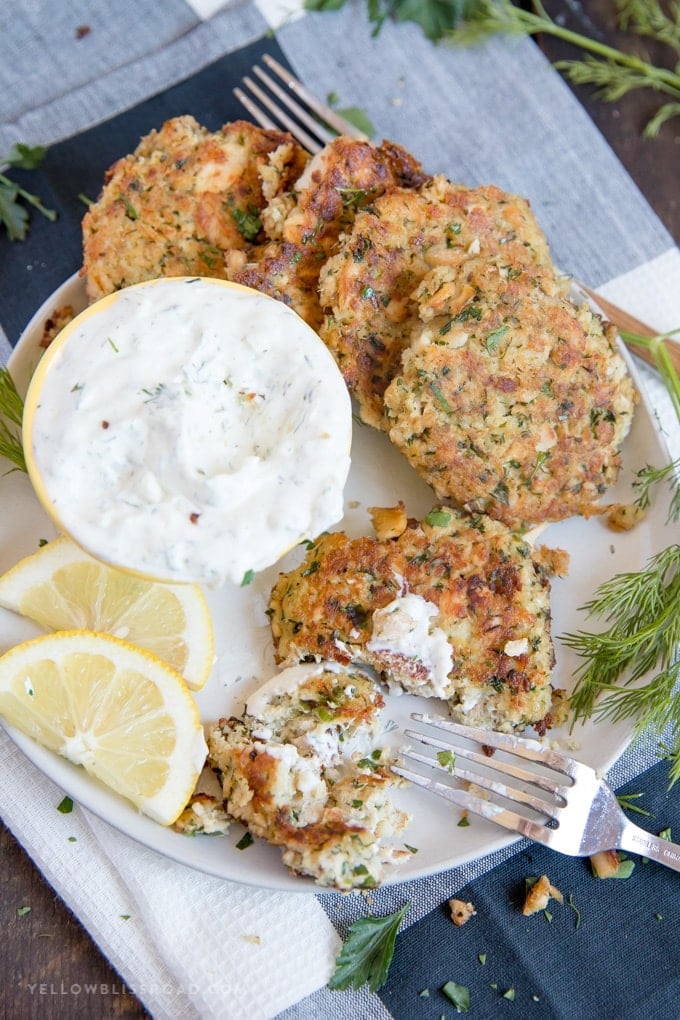 salmon patties on a plate with homemade tartar sauce and lemon wedges